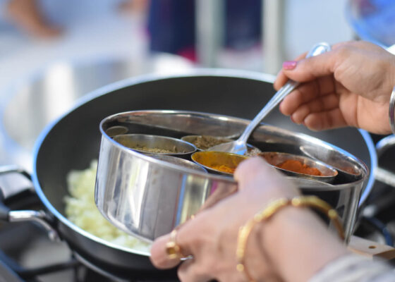 an up close image of someone cooking a meal - using a spoon to add spices to a dish