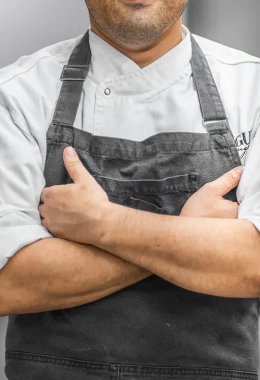 image of a man in chefs apron crossing his arms facing the camera