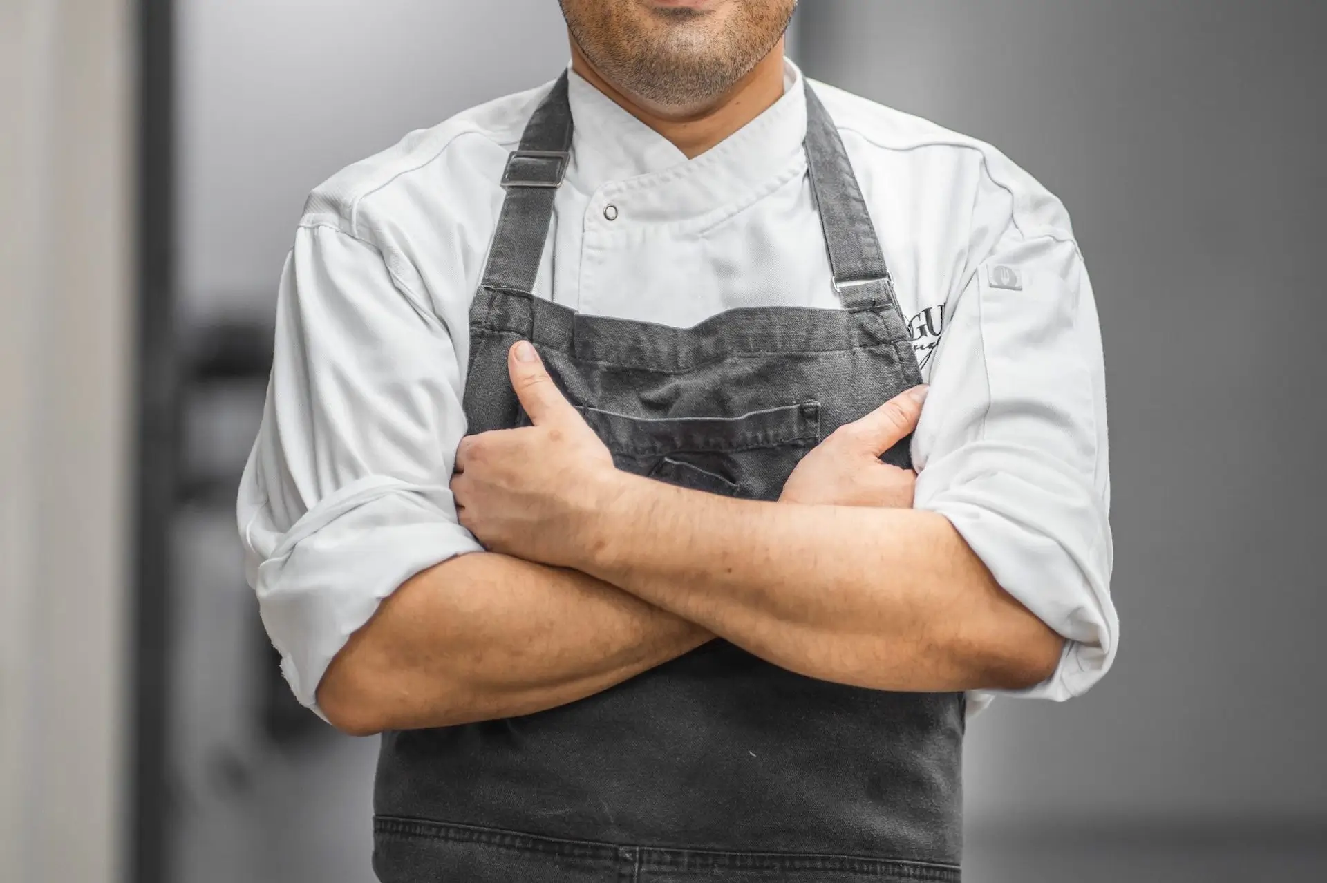 image of a man in chefs apron crossing his arms facing the camera