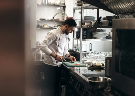 a chef cutting food in their kitchen. a way to cut the food could be considered kitchen hacks