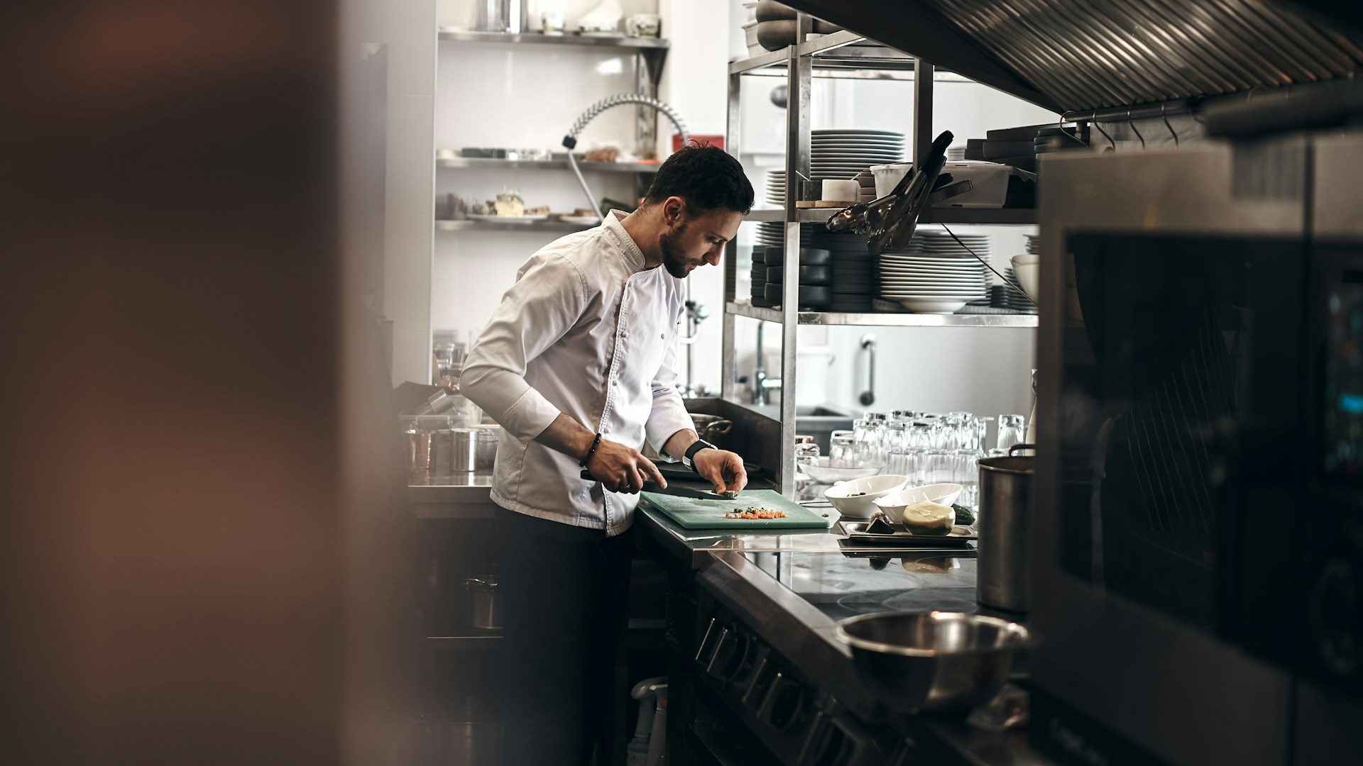 a chef cutting food in their kitchen. a way to cut the food could be considered kitchen hacks