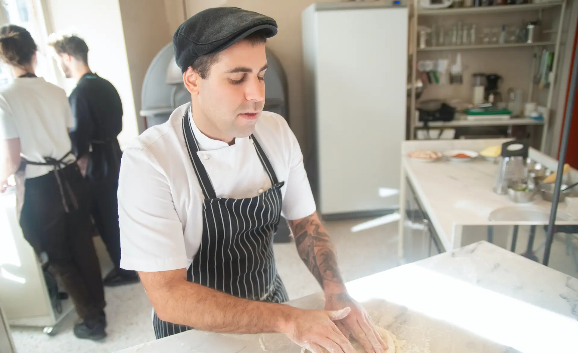 a man wearing a white chef top and a blue apron is preparing food.