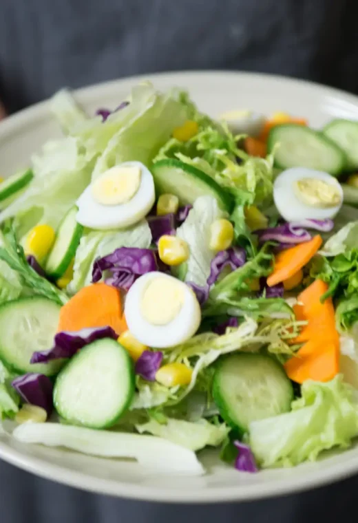 person holding a bright plate of salad