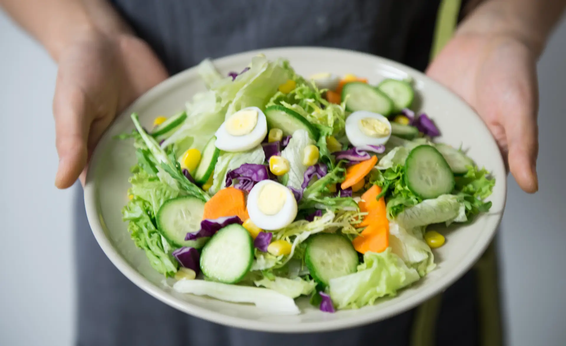 person holding a bright plate of salad