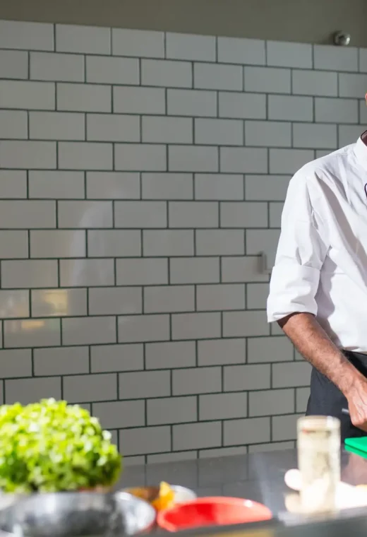 man in chef whites chopping some vegetables