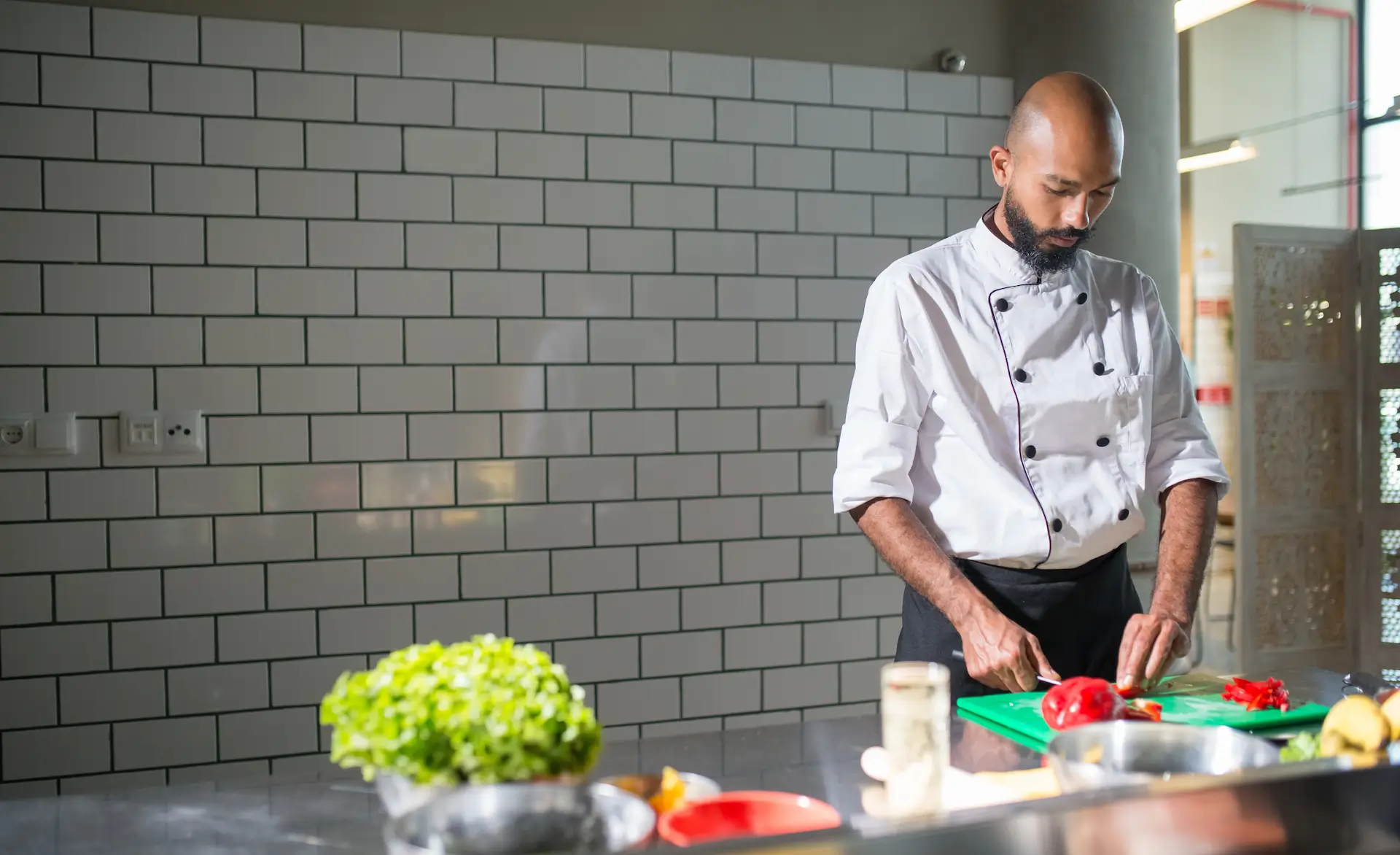 man in chef whites chopping some vegetables