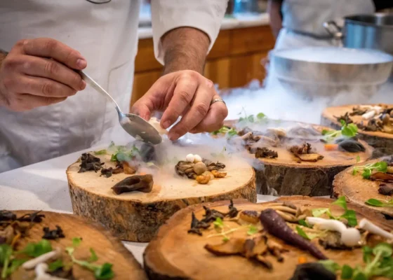 Someone serving food on a large wooden slab.