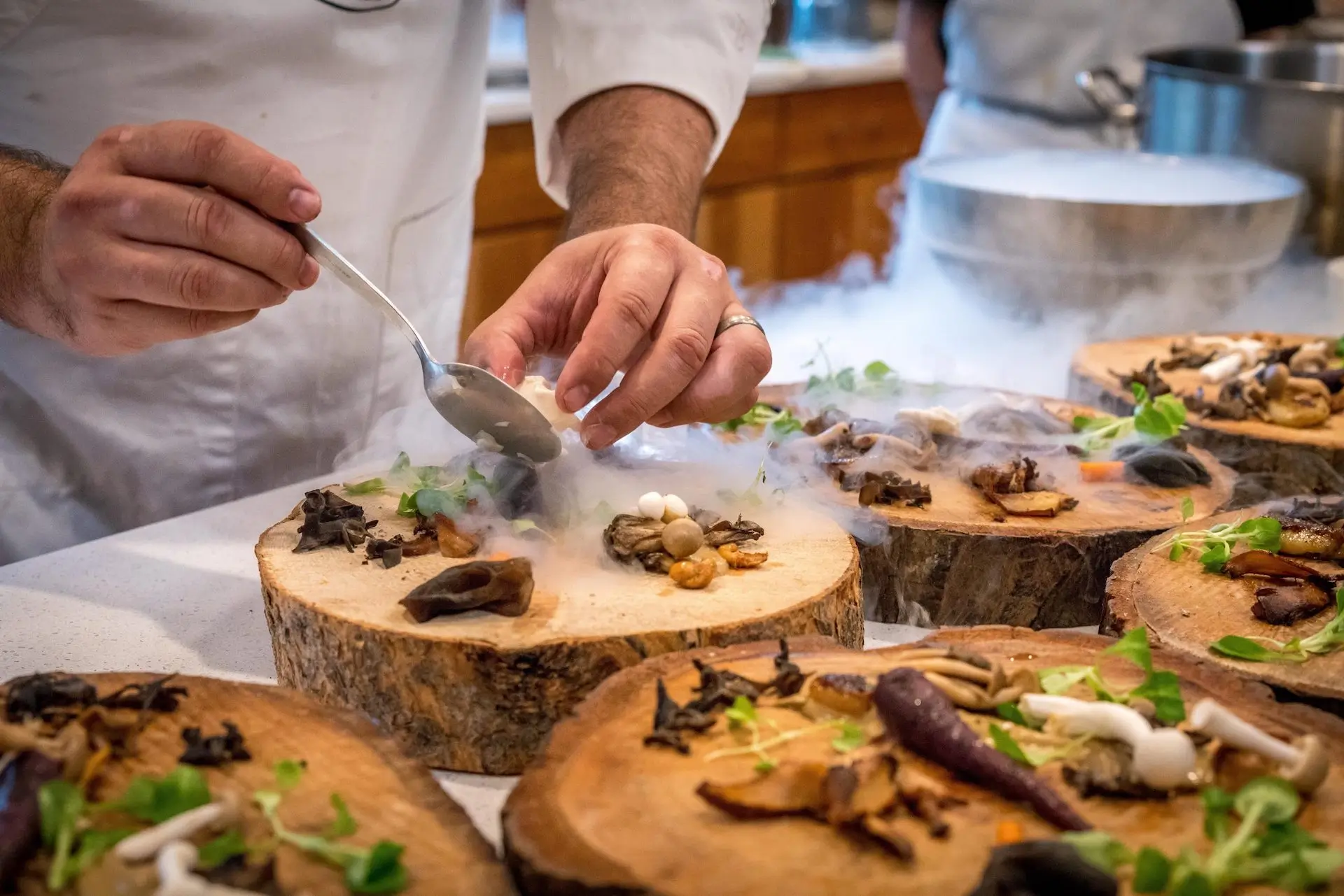 Someone serving food on a large wooden slab.