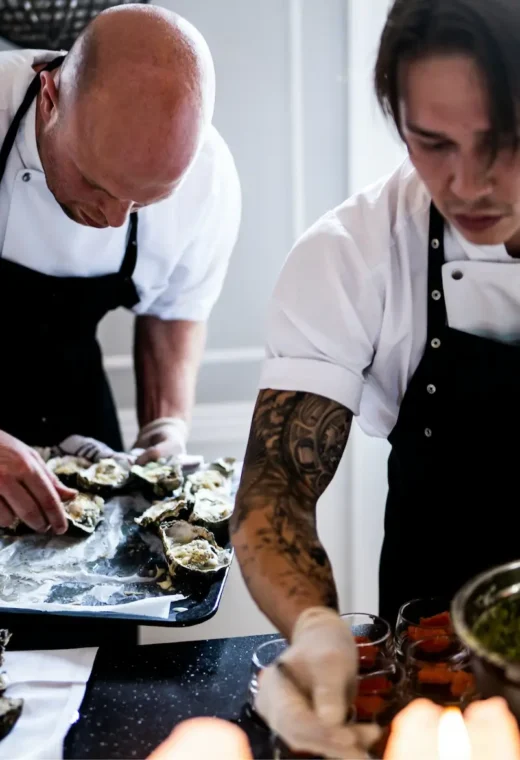 two caterers working on a meal, dishing it up on to trays