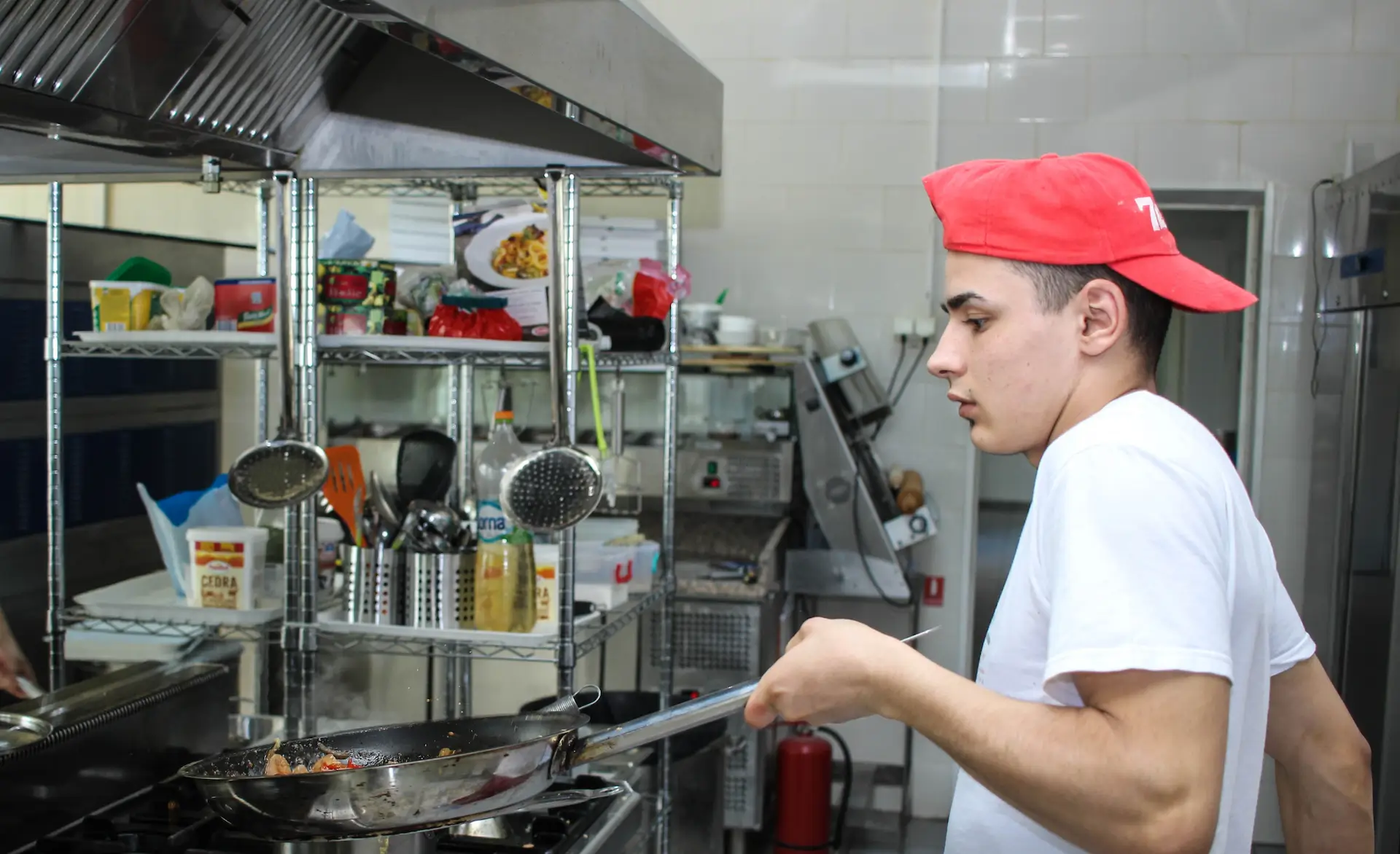 man in a red hat cooking over a stove