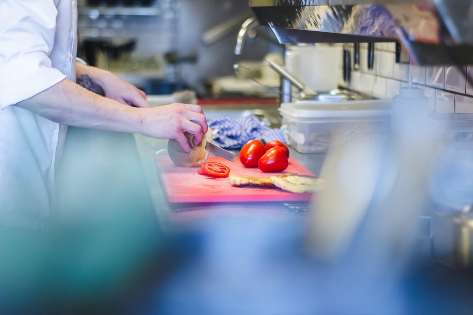 image showing a caterer chopping up tomatoes in a kitchen. wondering what catering in a care home is like? read more