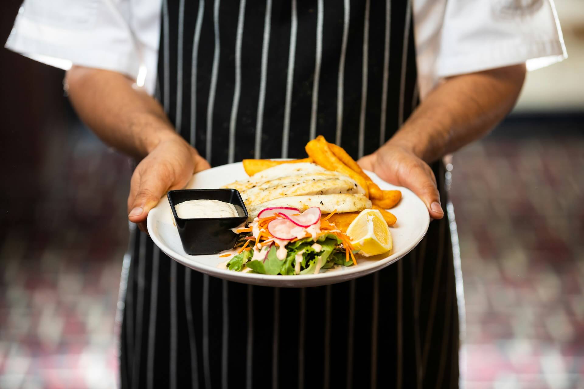 zoomed in image of a chef holding a dish that he has prepared