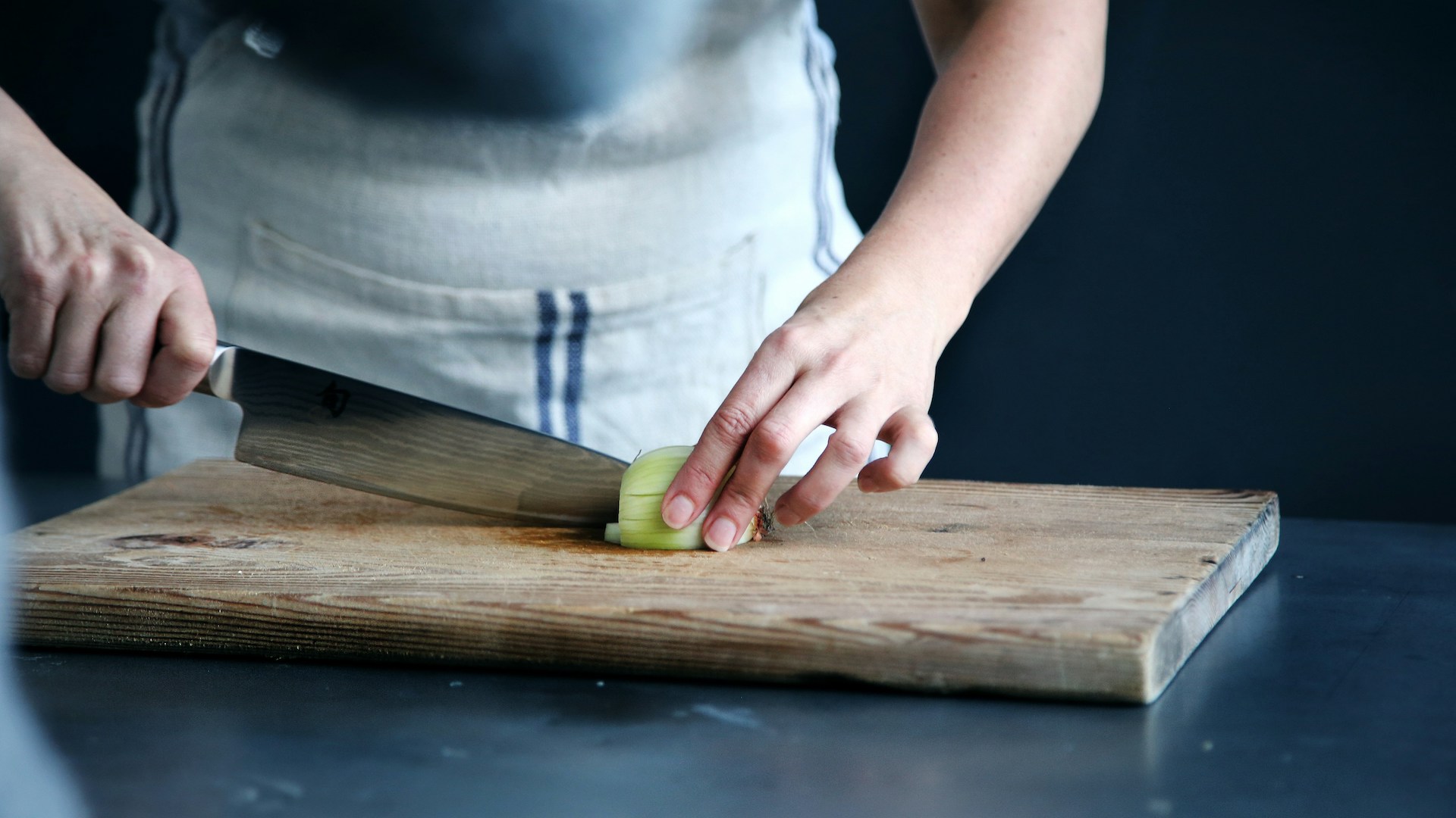 a person chopping an onion preparing food for defence catering